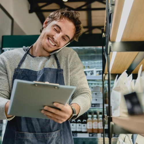 Business owner checks information on a tablet while working in an apron.